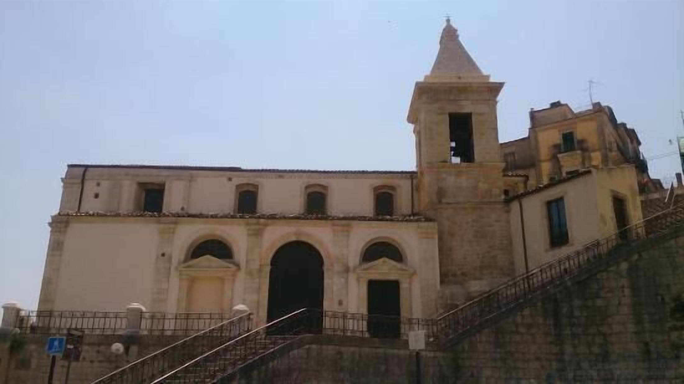 A historic building with a prominent bell tower and a staircase leading to the entrance.