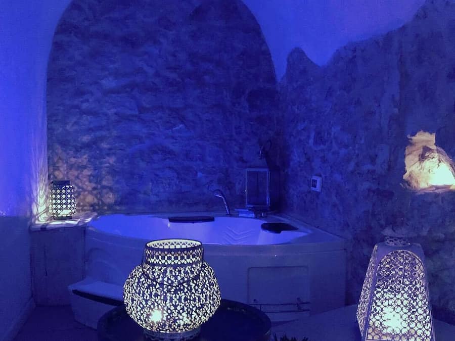 Un área de spa con un jacuzzi, una lámpara decorativa y un fondo de pared de piedra.