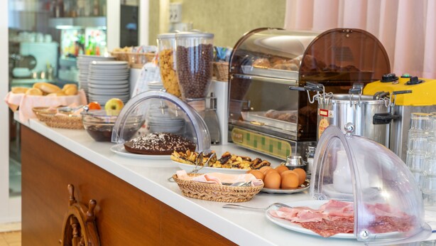 Un buffet proposant une variété d’aliments, notamment du pain, des pâtisseries et de la viande.