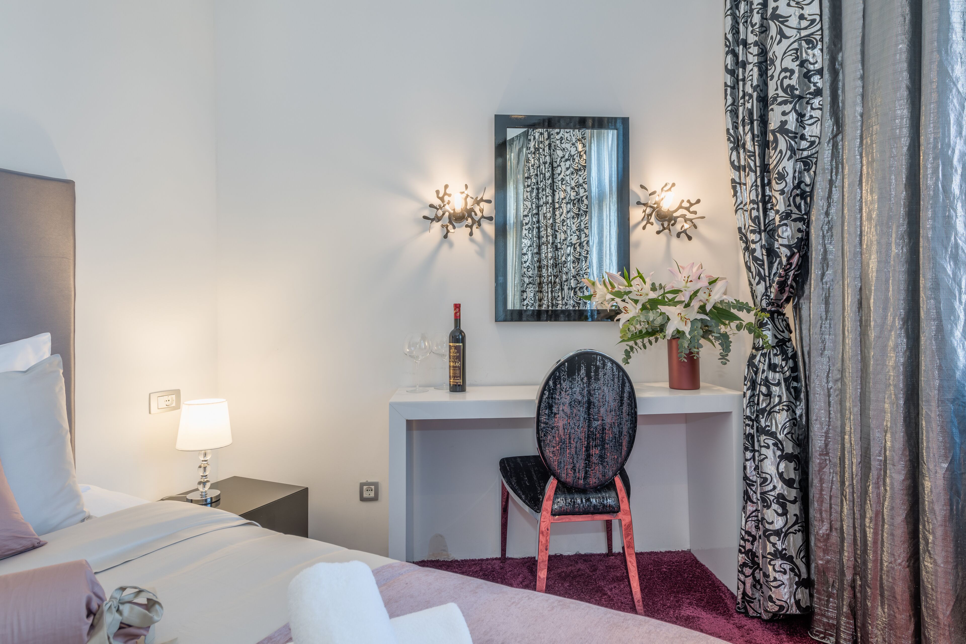 Ein Hotelzimmer mit Bett, Schreibtisch, Stuhl, Blumentopf und Spiegel.