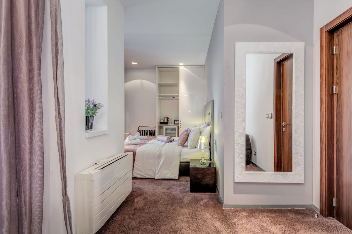Ein Schlafzimmer mit Bett, Nachttisch, Lampe und Spiegel an der Wand.