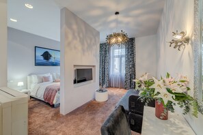 Ett modernt sovrum med en säng, en tv, ett soffbord och en vas med blommor.