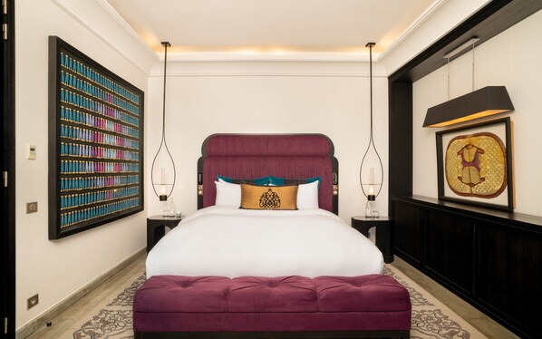 A bedroom with a large bed, two bedside tables, a wall-mounted bookshelf, and a framed picture. - STORY Rabat (Rabat)