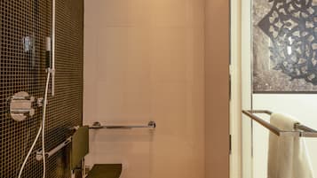 A shower with a glass door, a towel rack, and a wall-mounted towel dispenser.