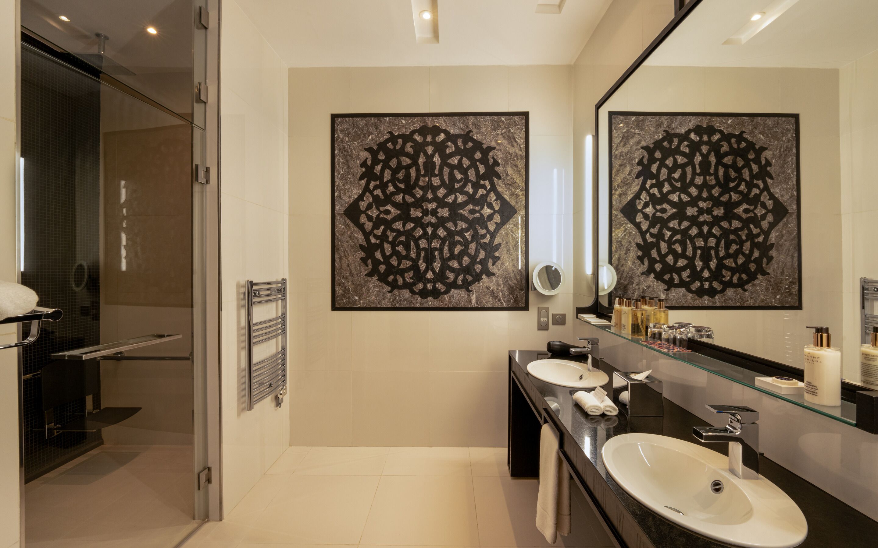 A modern bathroom with a glass shower enclosure, a large mirror, and two sinks.