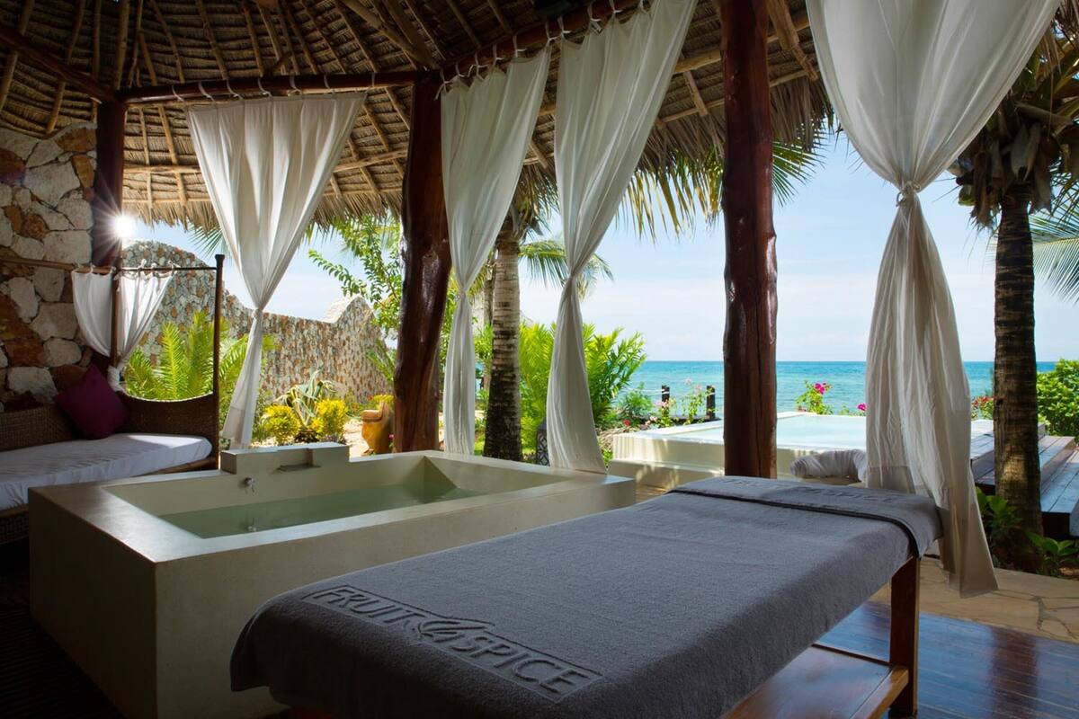A spa area with a bathtub, a massage table, and a view of the ocean.