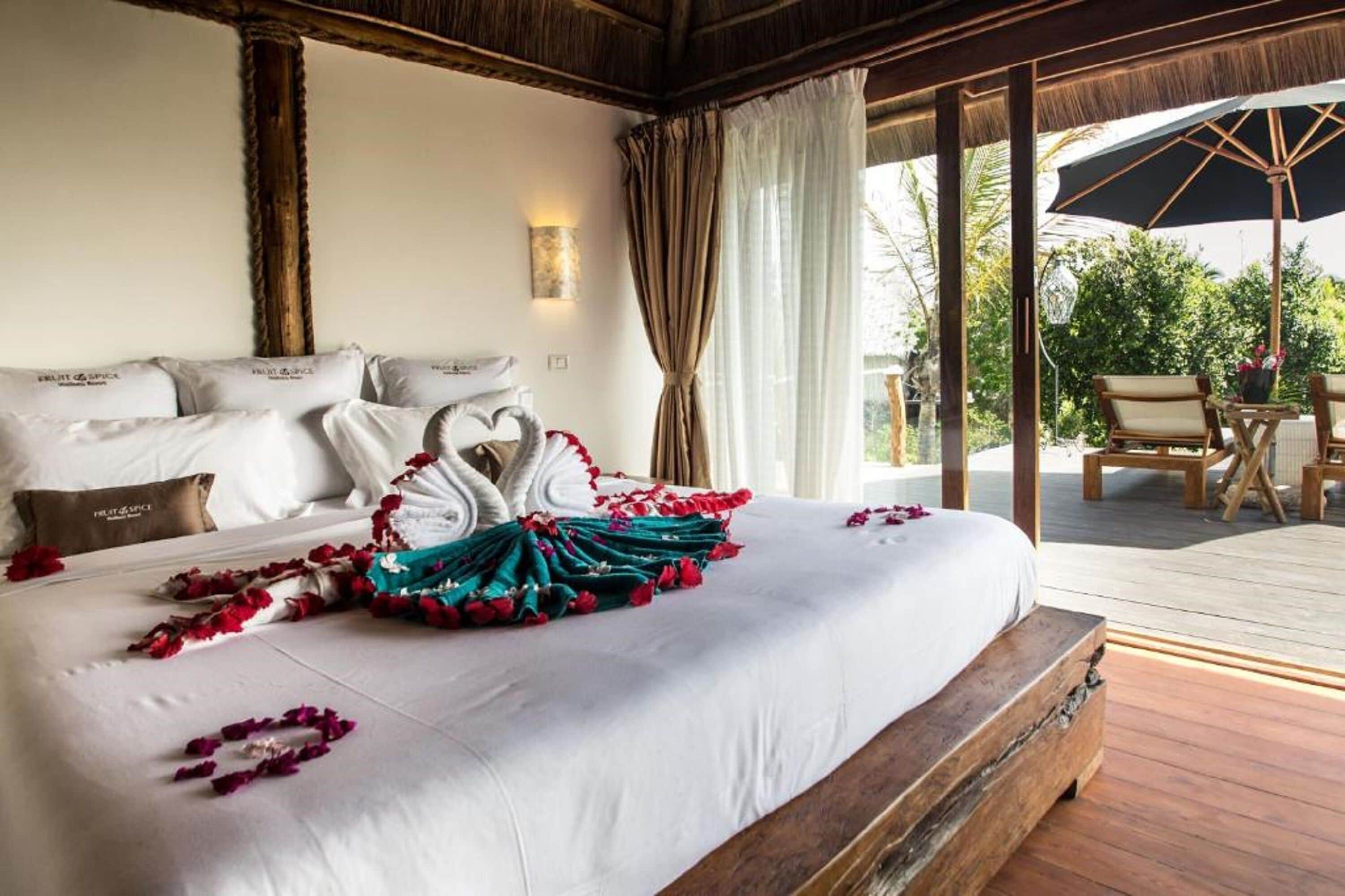 A hotel room with a large bed, a wooden headboard, and a view of the outdoor deck.