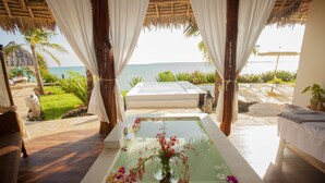 Zona relaxant d'un spa amb un bany d'hidromassatge, un ram de flors i vista a l'oceà.
