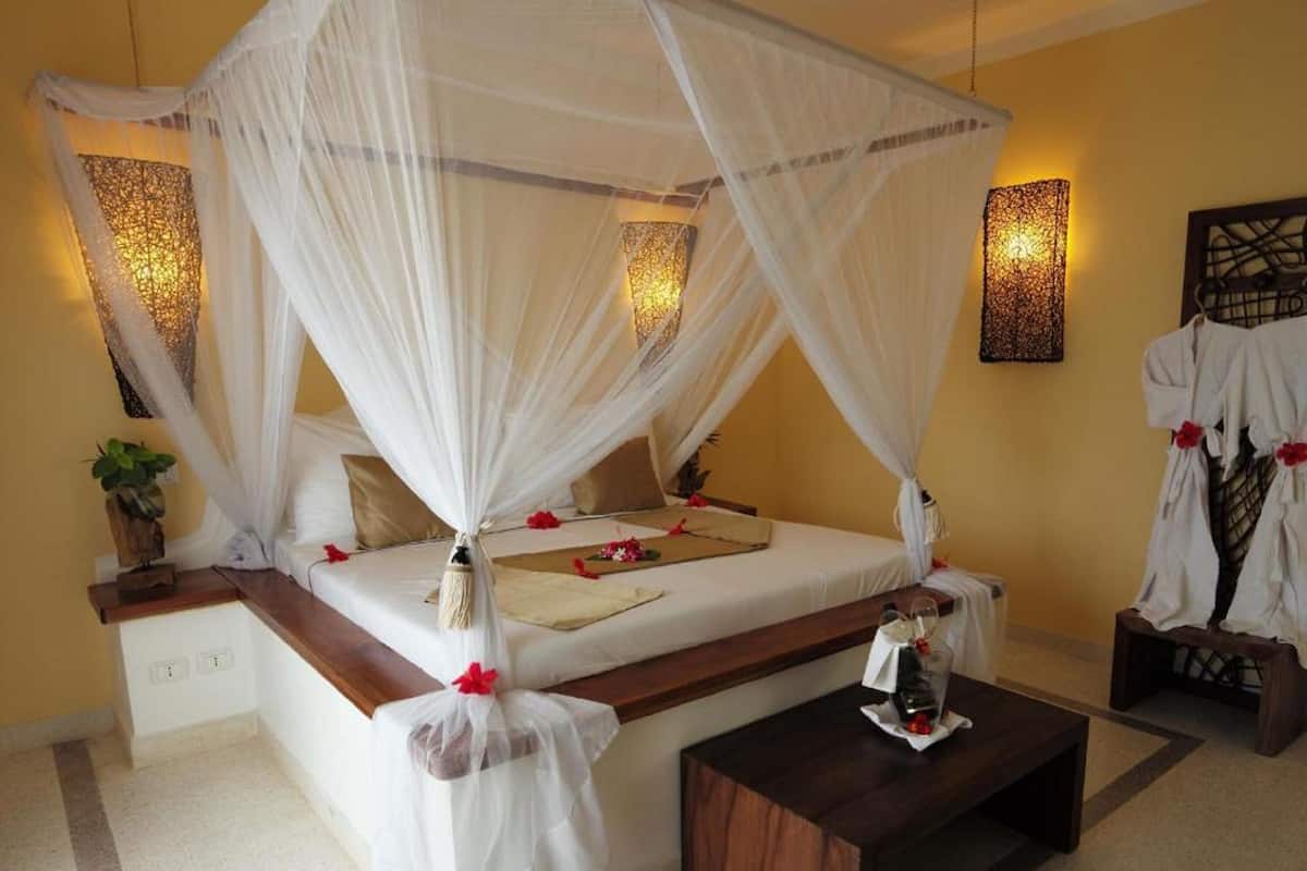 A four-poster canopy bed with a wooden headboard, a bedside table, and a nightstand.