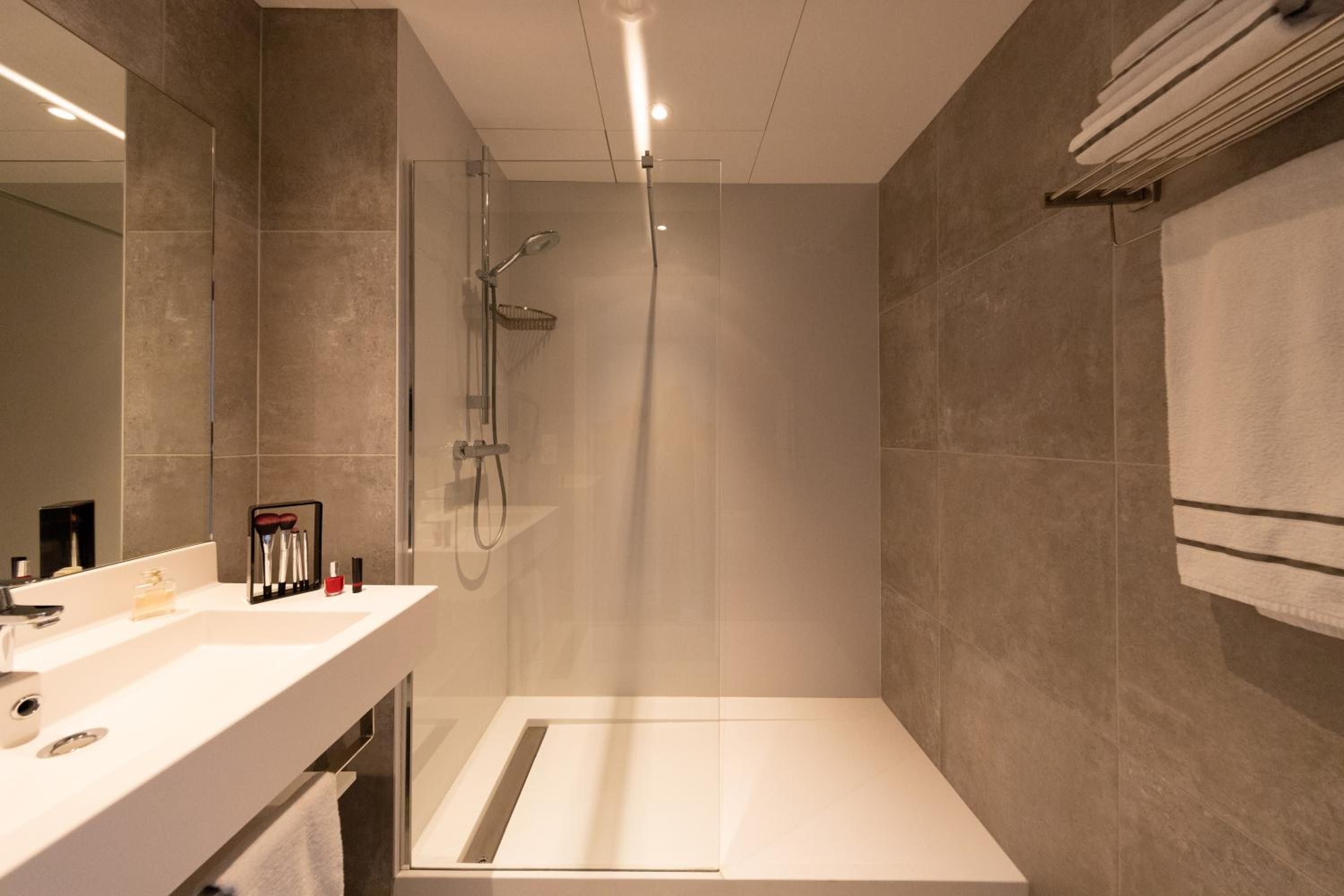 A modern bathroom with a shower, a vanity with a mirror, and a towel rack.