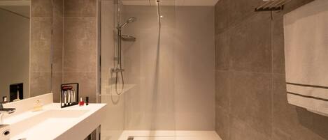 A modern bathroom with a shower, a vanity with a mirror, and a towel rack.