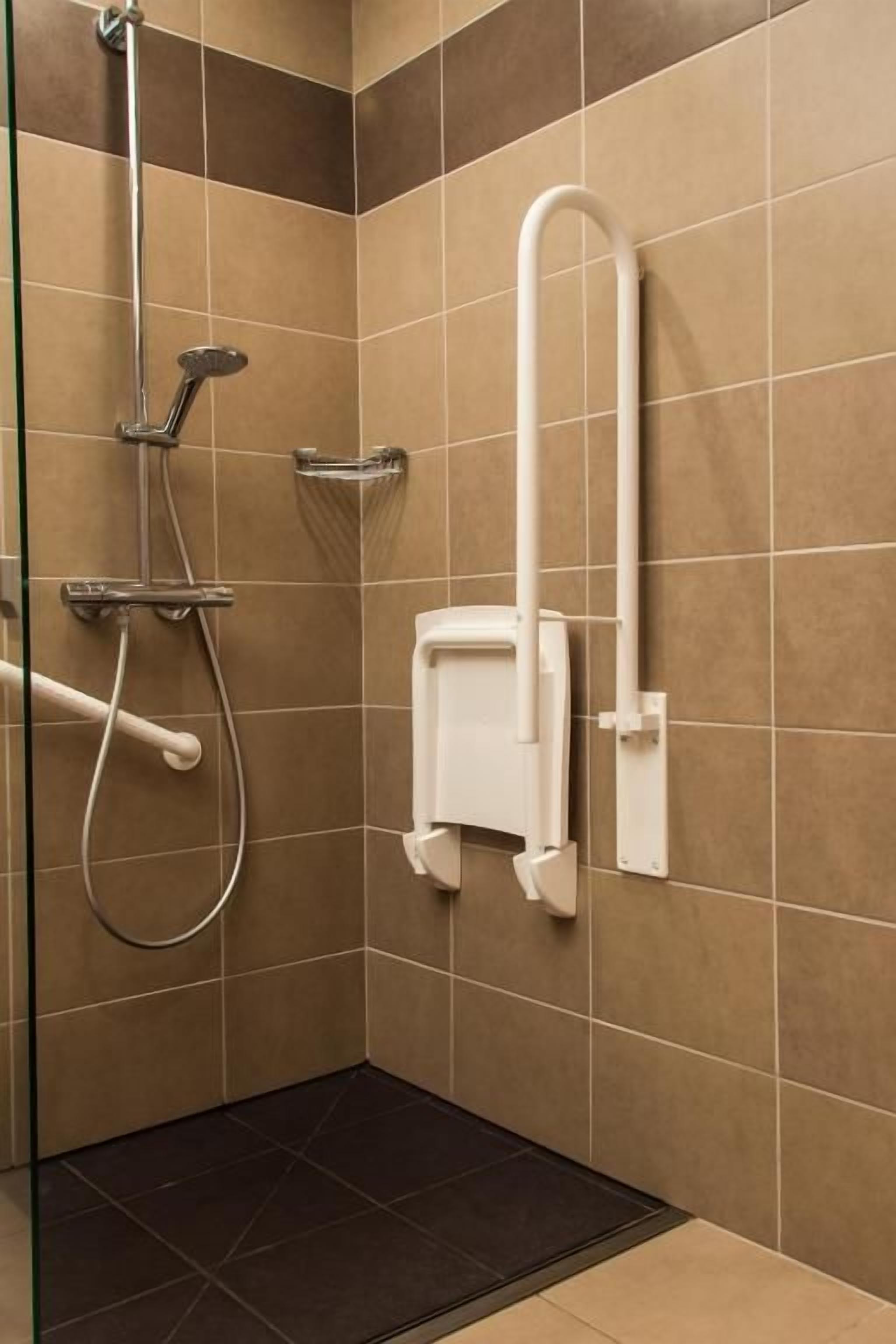 Zona de ducha con cabezal de ducha manual, grifo empotrado en la pared y panel de control de ducha manual blanco.