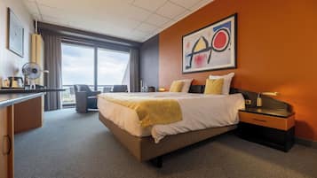 Habitación de hotel con una cama grande, un escritorio, una silla y una ventana con vistas.