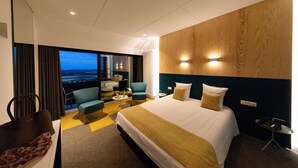 A hotel room with a large bed, a seating area with a view, and a small table with a phone. - Le Floreal Panoramique (Tournai)
