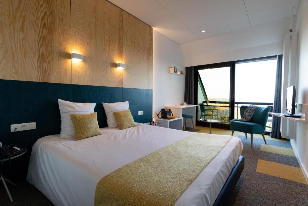 Une chambre d’hôtel avec un grand lit, un bureau, une chaise et une vue sur l’extérieur.