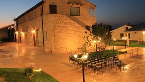 Un edificio de piedra con patio, asientos al aire libre y una entrada bien iluminada.