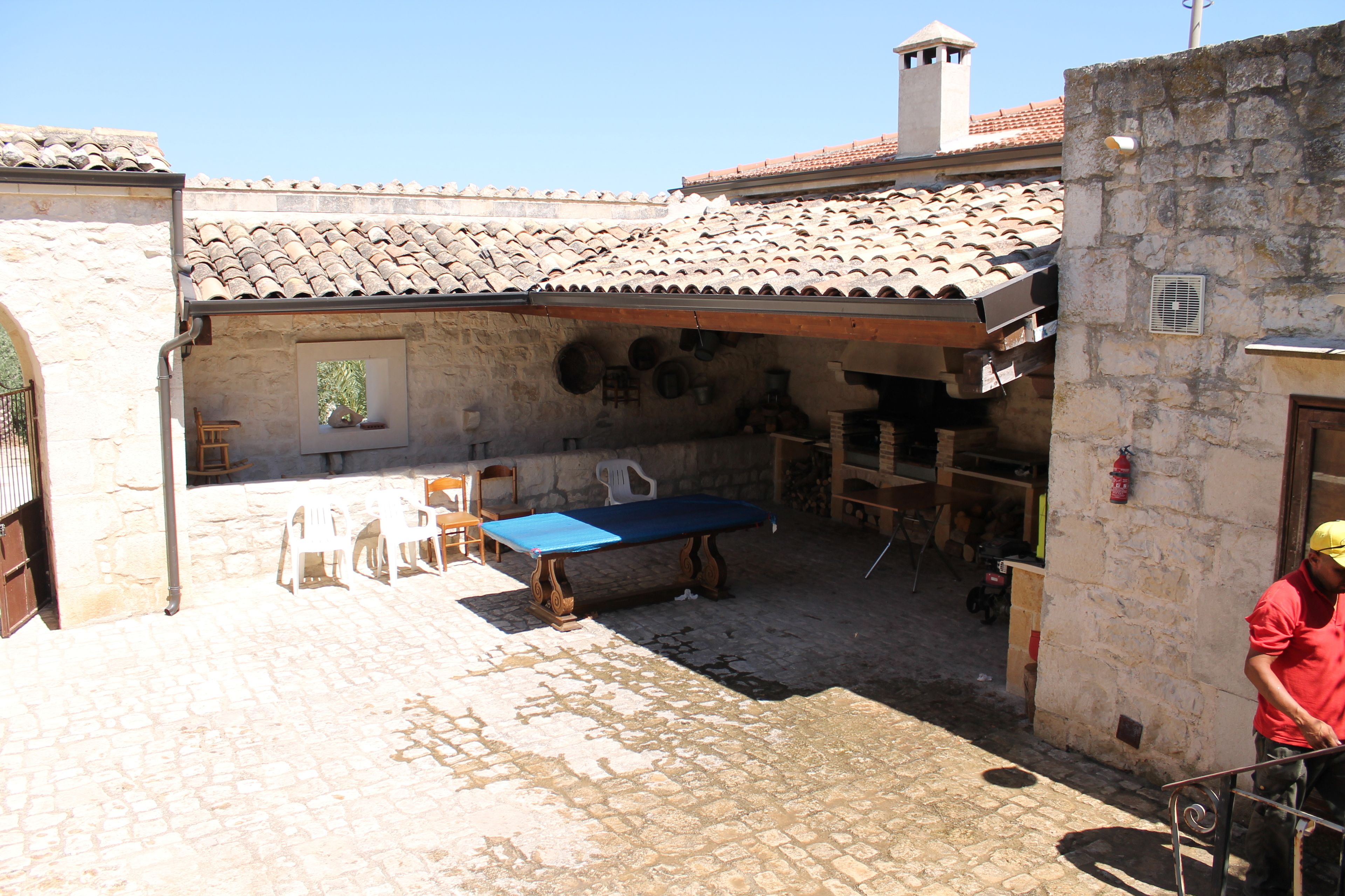 A courtyard with a pool table, chairs, and a stone wall.