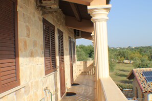 A stone building with wooden shutters, a balcony with a view of greenery, and a solar panel on the roof. - Le due Palme - Il Paradiso di Adamo (Modica)