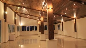 Una galería amplia con piso pulido, vigas de madera y luces fijadas en la pared.