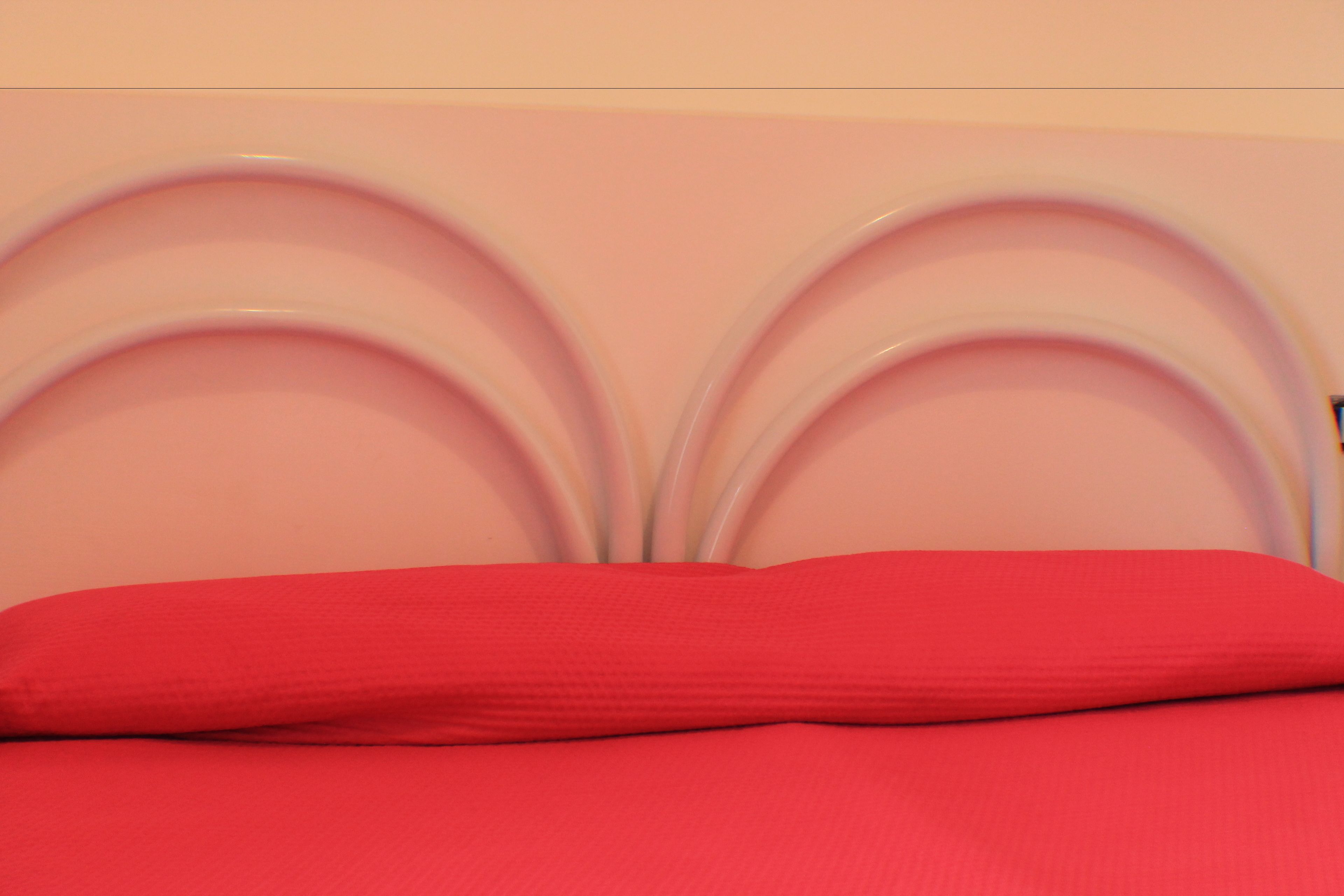 A bed with a red mattress and a headboard with a curved design.