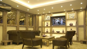 A cozy living room with a television, comfortable seating, and decorative vases. - Comfort Elite Hotels Old City (Istanbul)