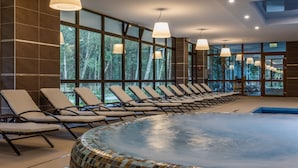 Un área de piscina interior moderna con sillones de descanso y grandes ventanales.