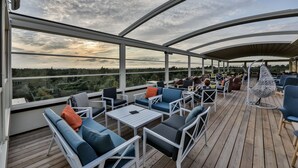 Un espacio de estar techado al aire libre con mobiliario blanco y vistas al paisaje.