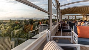 Un área de estar al aire libre de diseño moderno con una vista panorámica de un paisaje boscoso.