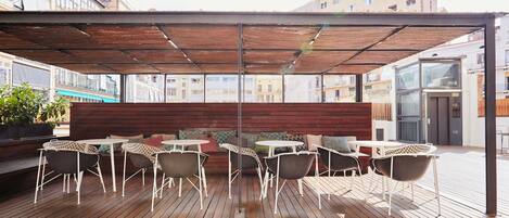 An outdoor seating area with wooden flooring and a covered section.