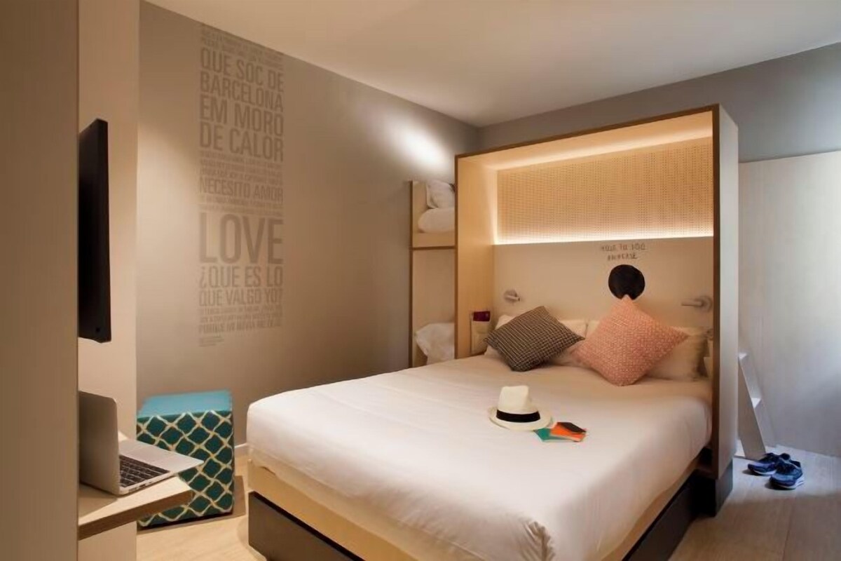 A modern bedroom with a bed, bedside table, and a wall with motivational quotes.