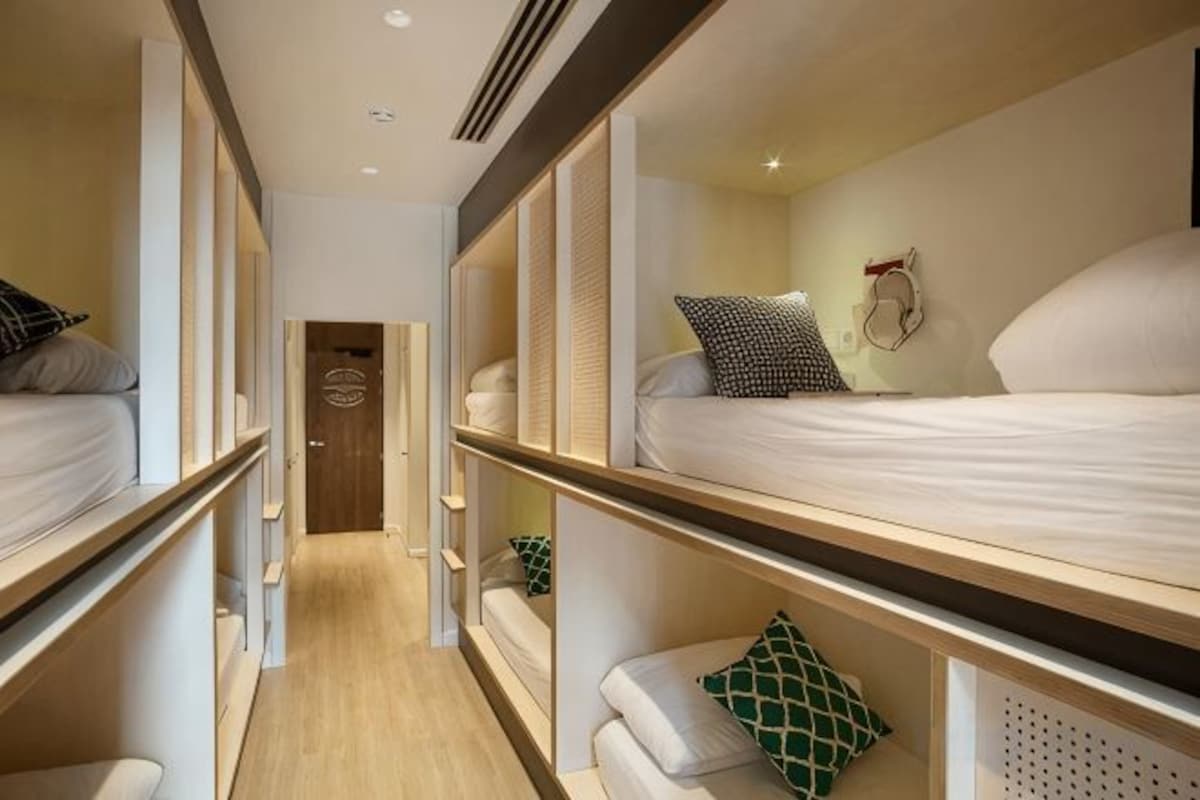 Una habitación de hotel con literas, suelo de madera y una puerta en el centro.