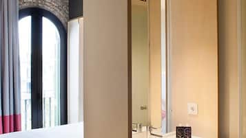 Een hotelkamer met een groot raam, een spiegel en een klein tafeltje met toiletartikelen.