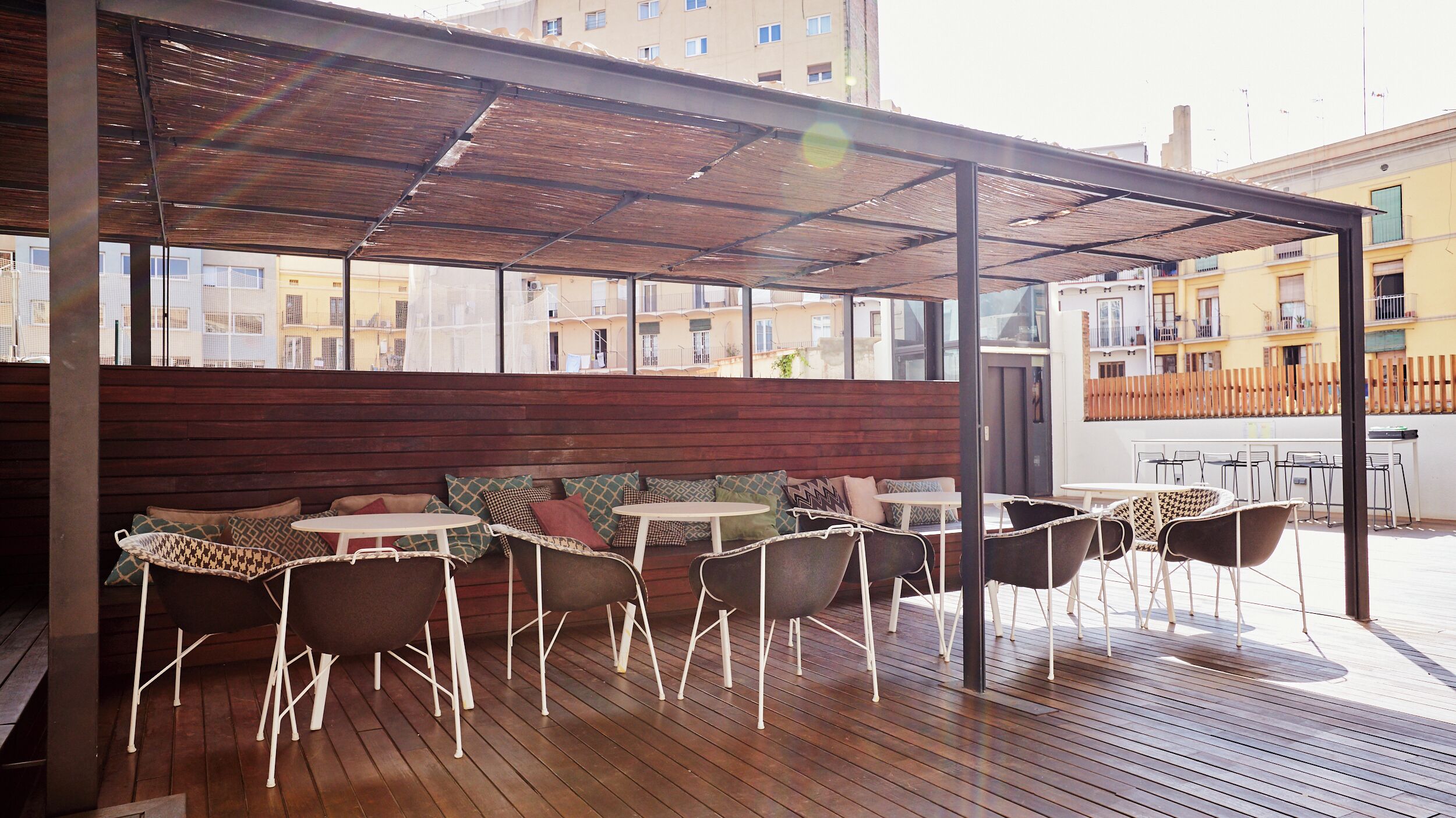 Een terras met houten vloer, comfortabele banken en tafels.