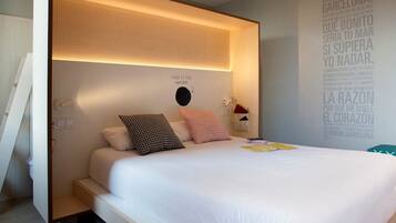 Un dormitorio moderno con una cama grande, cabecera con diseño perforado, una mesita de noche y una pared con citas motivacionales.
