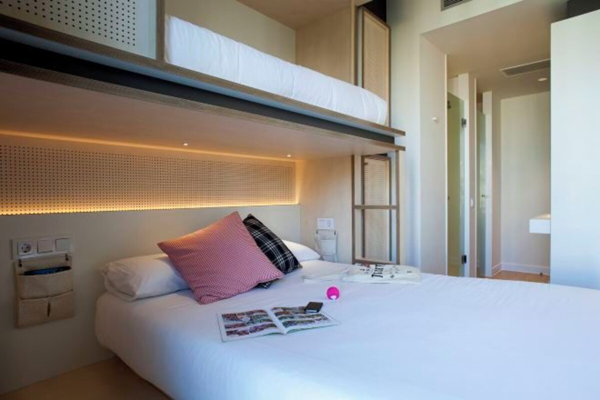 A hotel room with a large bed, a bedside table, a nightstand, and a window.