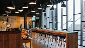 A modern bar area with wooden stools, a long counter, and pendant lighting. - TOC Hostel Barcelona (Barcelona)