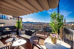A terrace with outdoor seating, a view of the city, and a clock tower in the background. - Palazzo Alfieri Residenza d’epoca  (Florence)