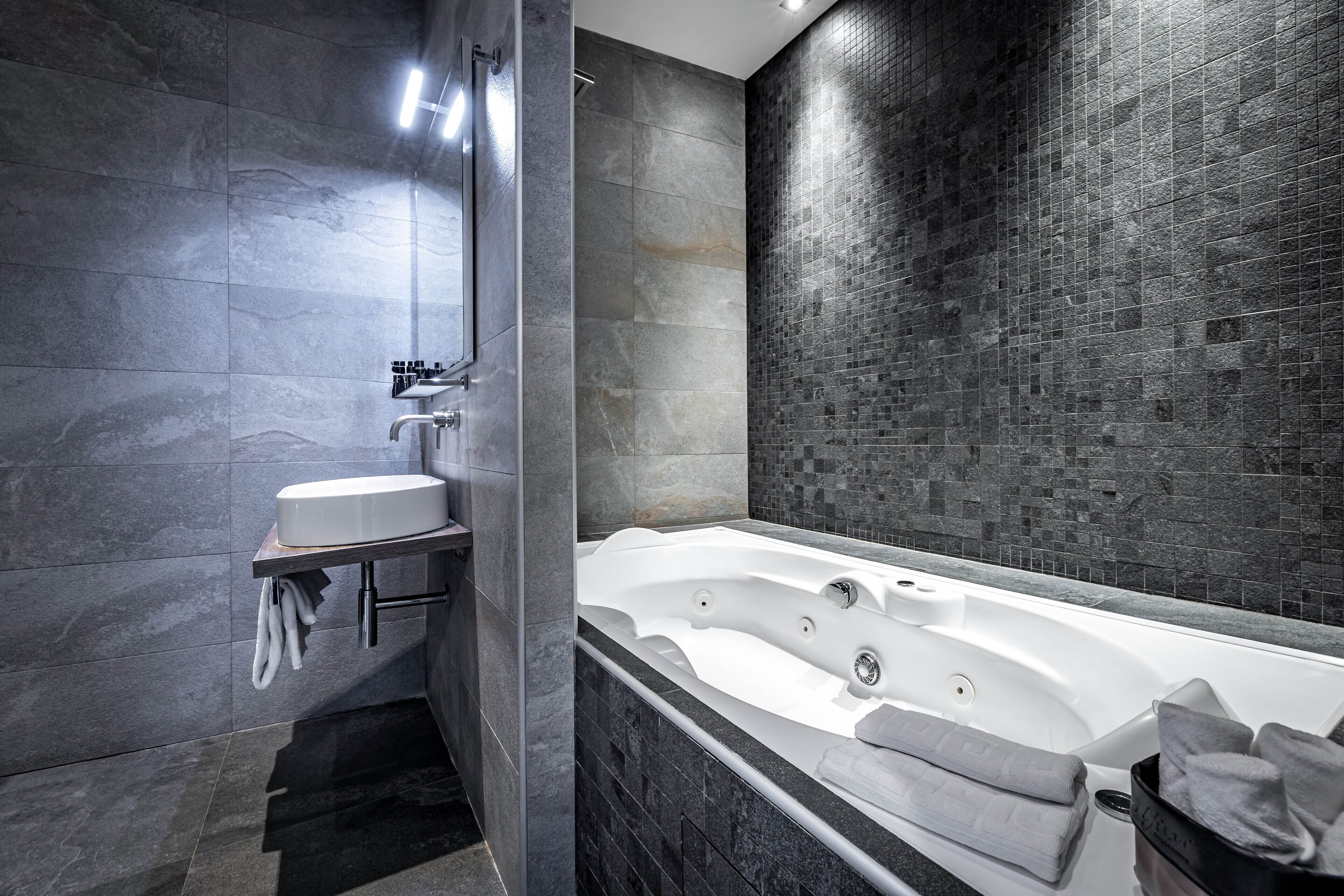 A modern bathroom with a large bathtub, a sink, and a shower area.