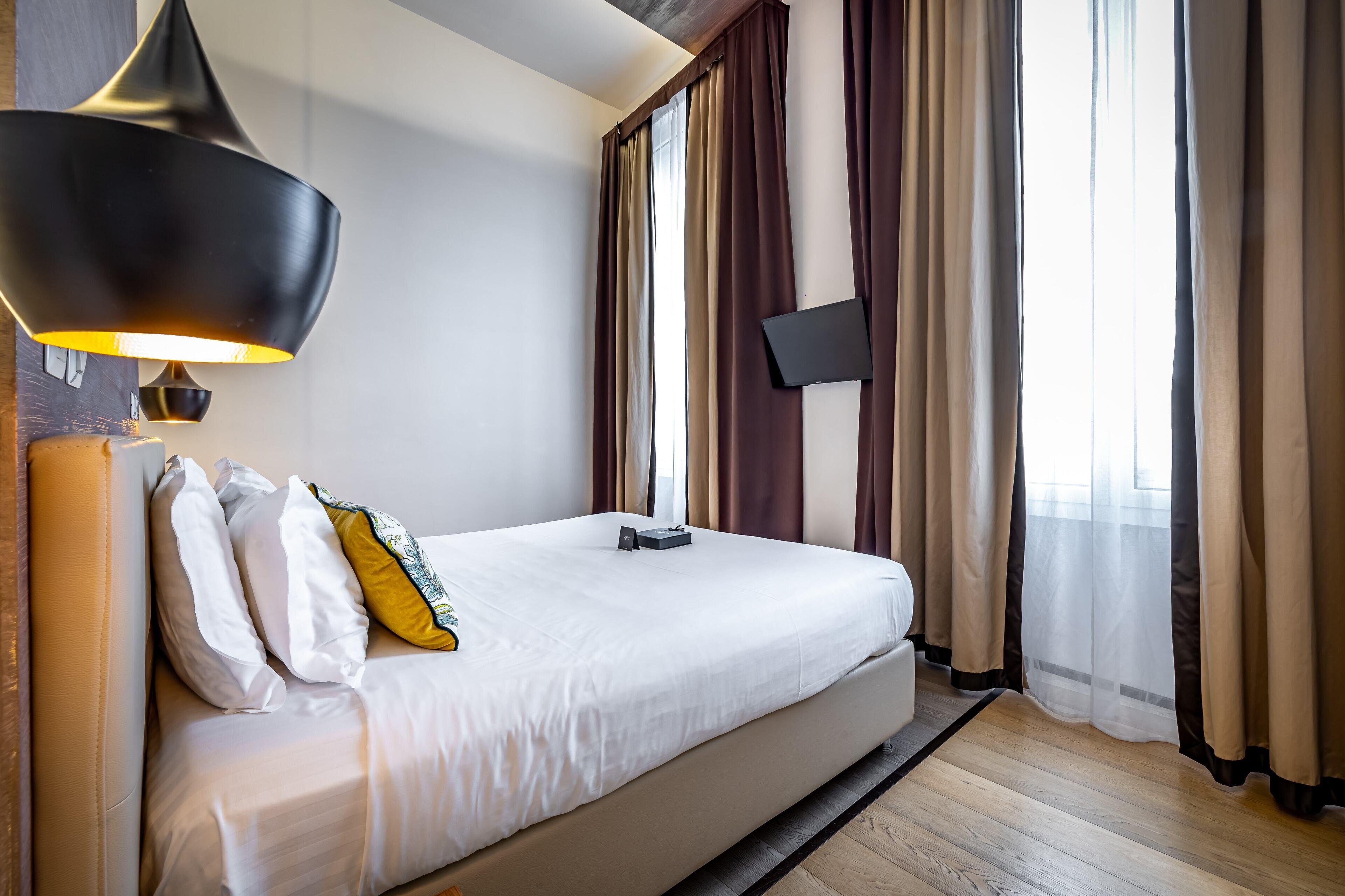 Ein Hotelzimmer mit einem Bett, einem Flachbildfernseher und einer modernen Lampe.
