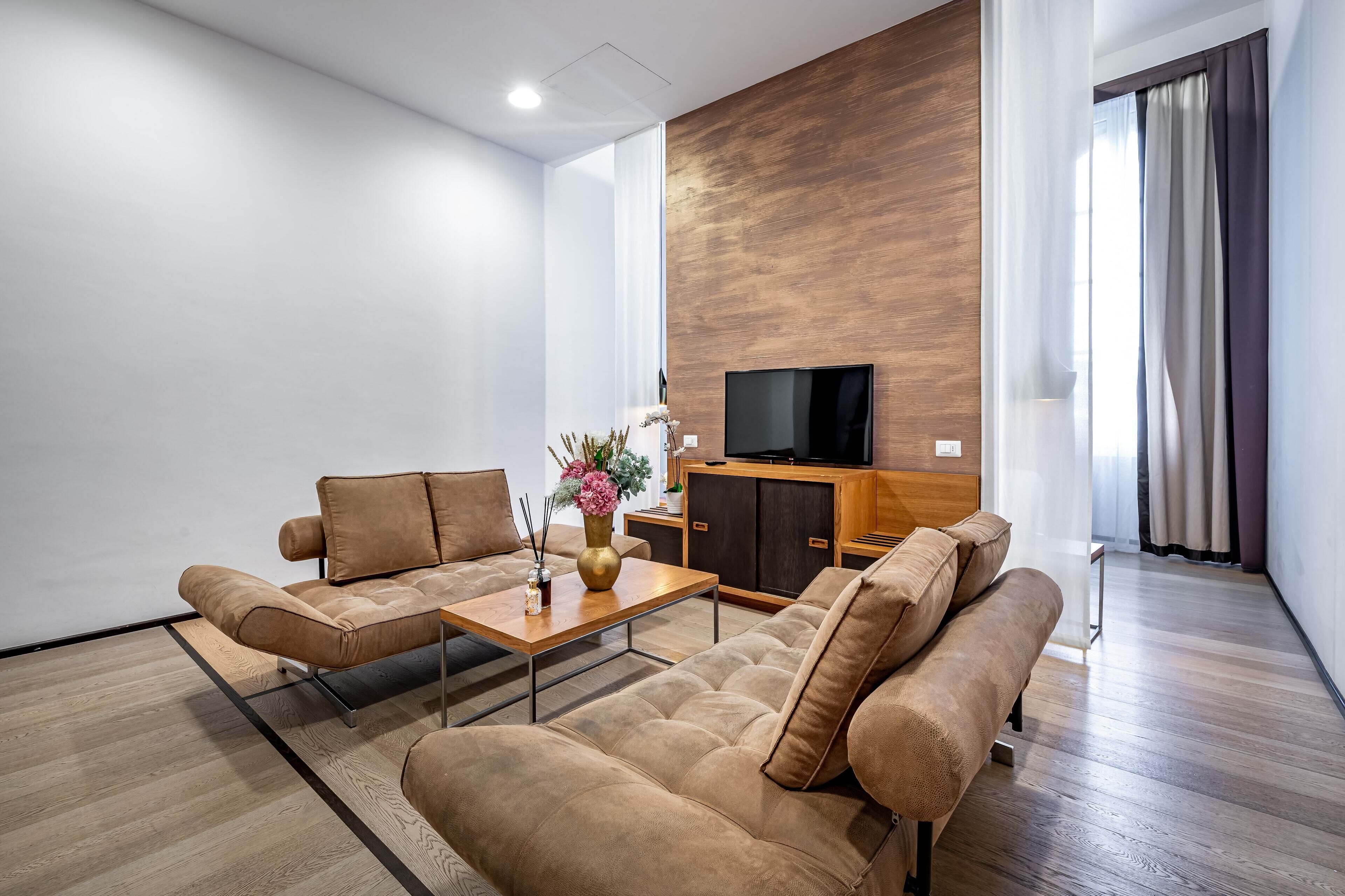 A modern living room with a sofa set, a coffee table, a TV, and a wooden accent wall.