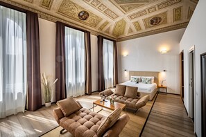 A spacious room with a large bed, two sofas, a coffee table, and a potted plant. - Palazzo Alfieri Residenza d’epoca  (Florence)