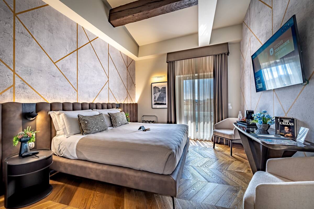 Una camera d'albergo moderna con un letto grande, una scrivania con televisore a schermo piatto e vista sulla città.