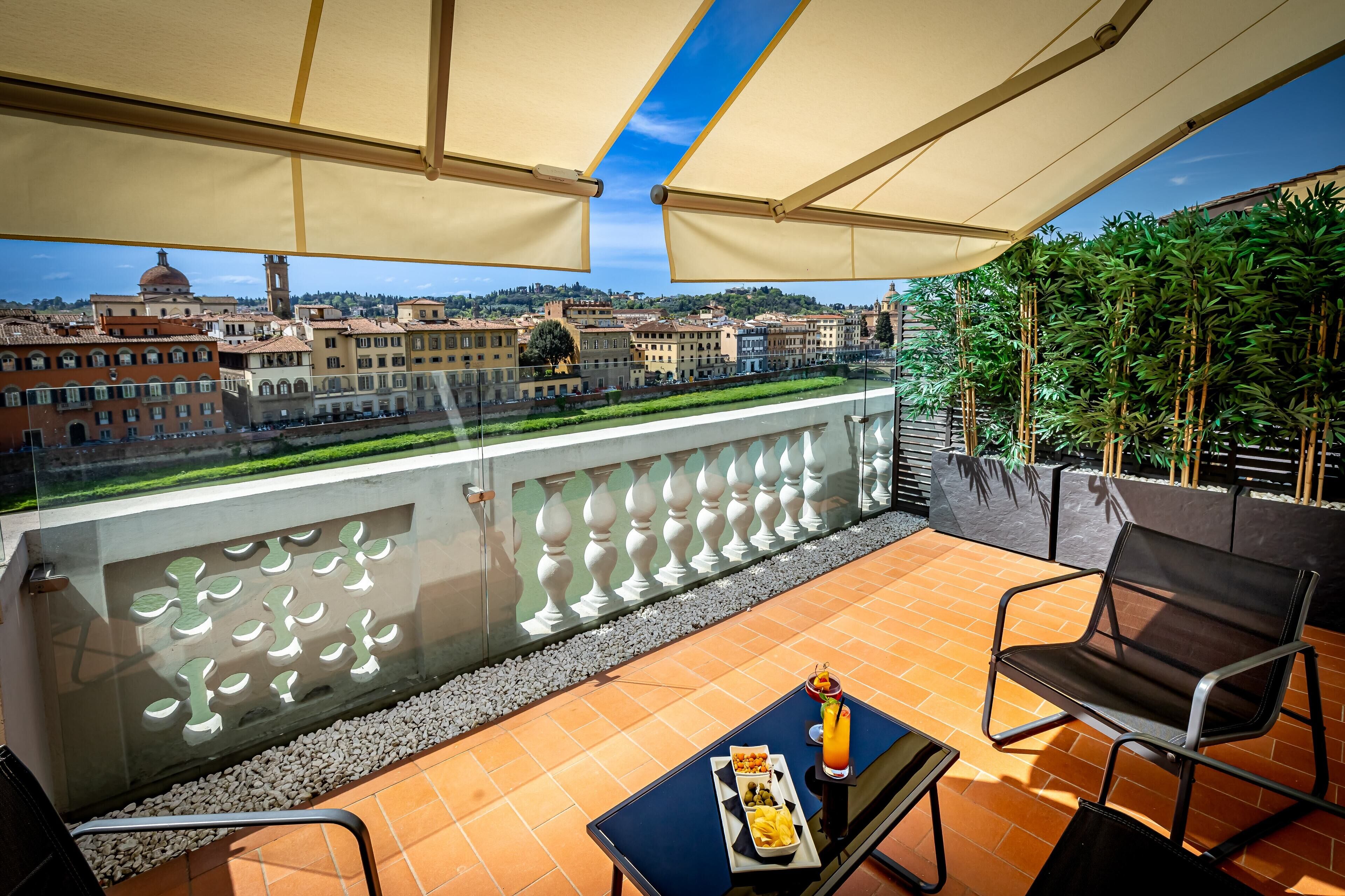 A balcony with a table, chairs, and a tray of food.