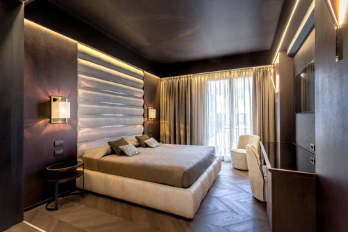 Una camera d'albergo moderna con un letto grande, un'area salotto con una poltrona e una scrivania.