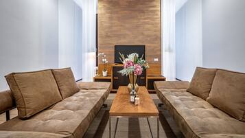 Una sala de estar moderna con dos sofás marrones, una mesa de centro de madera y un jarrón decorativo con flores.