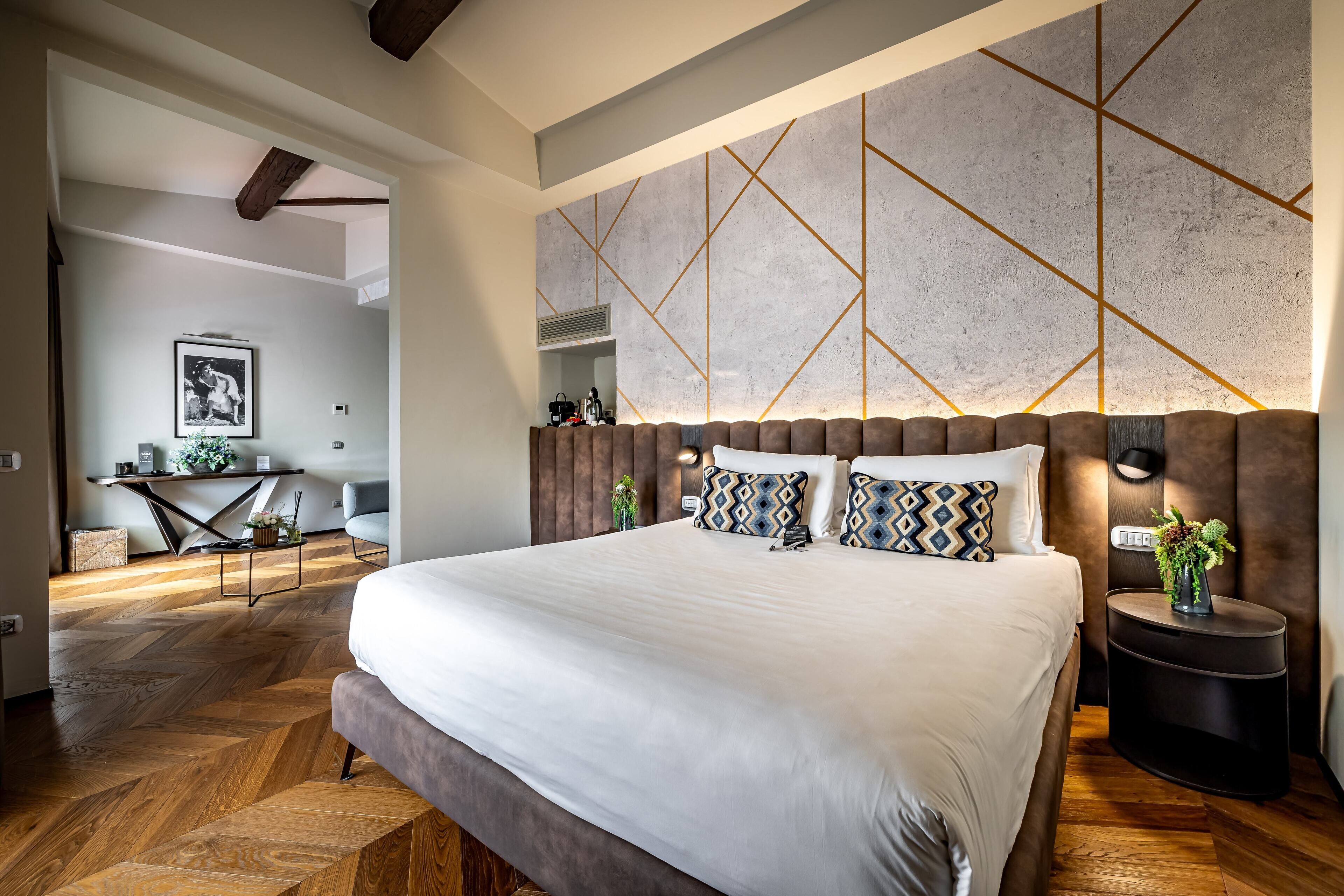 Un dormitorio moderno con una cama grande, suelo de madera y un diseño geométrico en la pared.