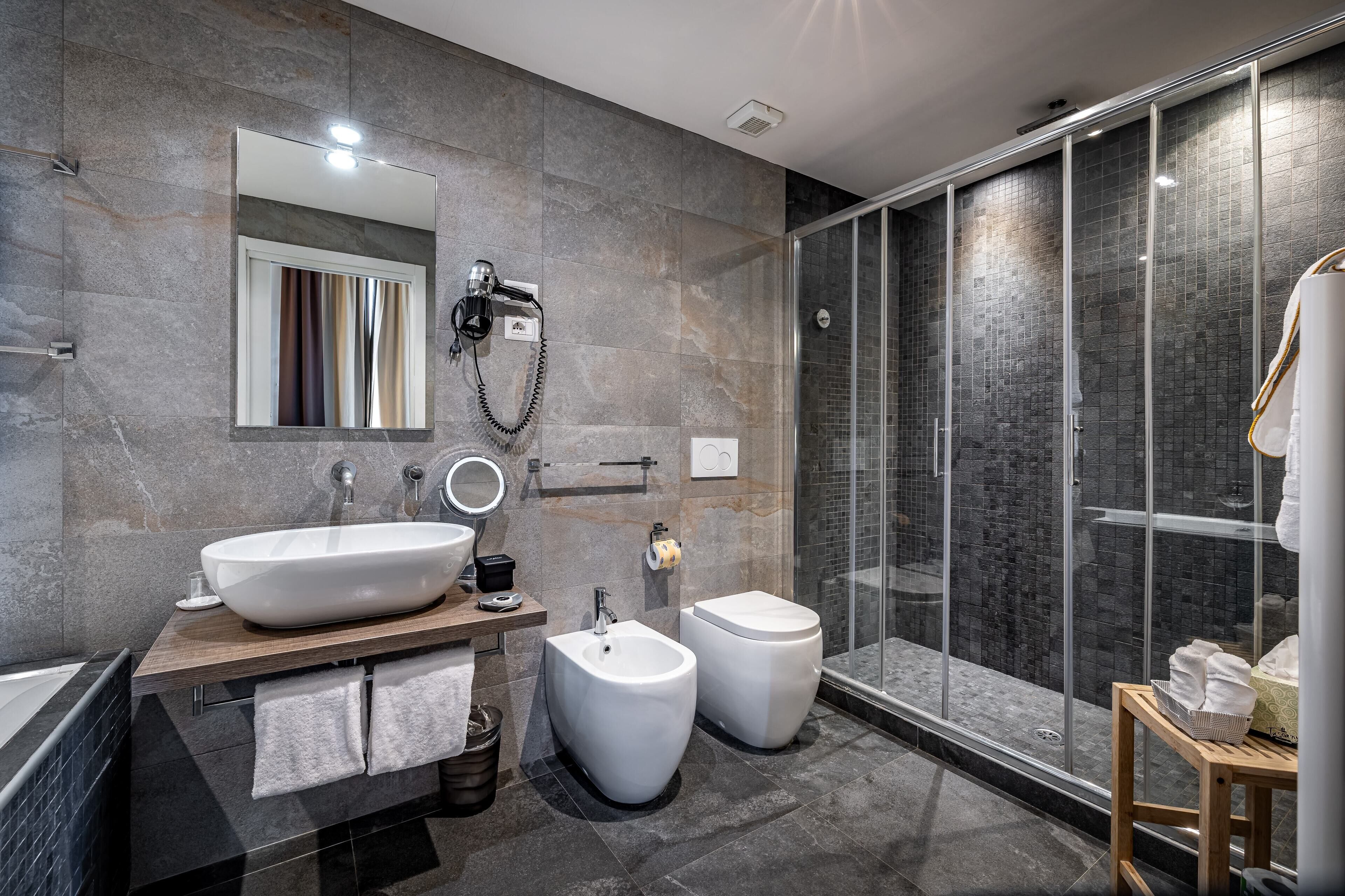 Une salle de bain moderne dotée d’un grand lavabo, d’un bidet et d’une douche à parois de verre.