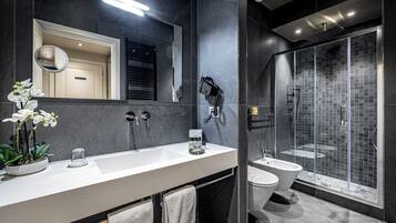 A modern bathroom with a large mirror, a sink, a toilet, and a glass-enclosed shower.