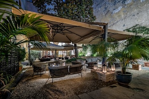 An outdoor seating area with umbrellas, wicker furniture, and potted plants. - Palazzo Alfieri Residenza d’epoca  (Florence)