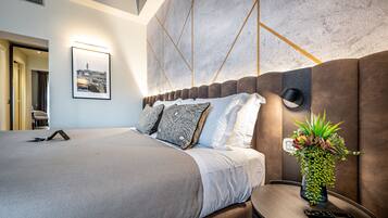 Una moderna camera d'hotel con un letto grande, un comodino con un telecomando e una lampada a parete.